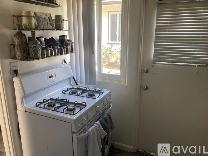 A white gas stove is in a small kitchen with a window and a door.