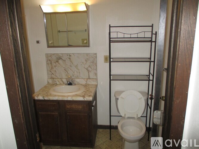 A bathroom with a toilet, sink, and mirror.