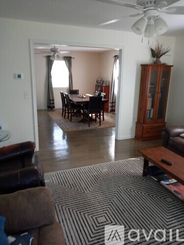 A living room with a brown couch and a wooden cabinet.
