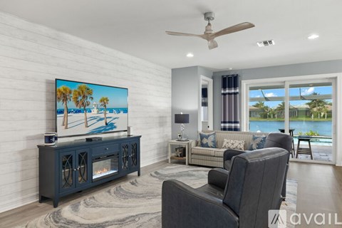 A living room with a grey couch, a television, and a painting of a beach scene.