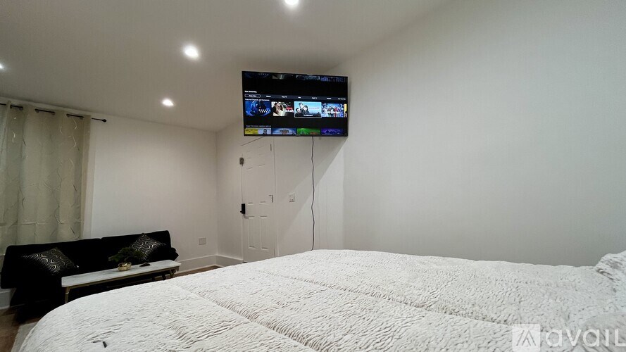 A bedroom with a large bed and a television mounted on the wall.
