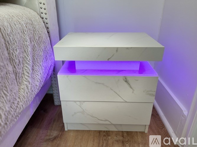 A white marble bedside table with a drawer and a shelf.