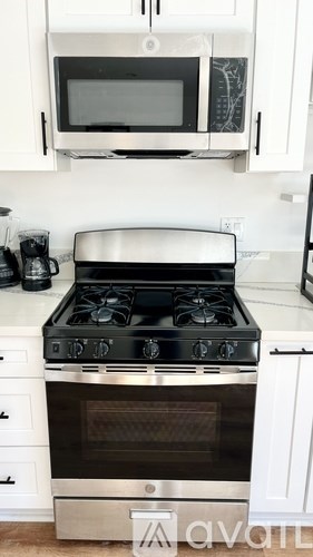 A black and silver stove in a kitchen with white cabinets.