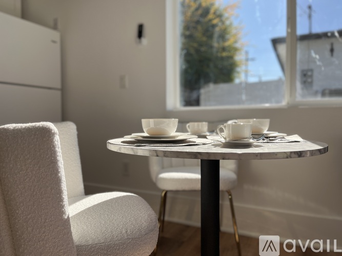 A table with two cups and saucers on it sits in front of a window.