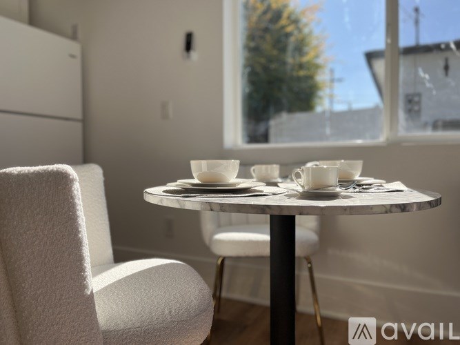 A table with two cups and saucers on it sits in front of a window.