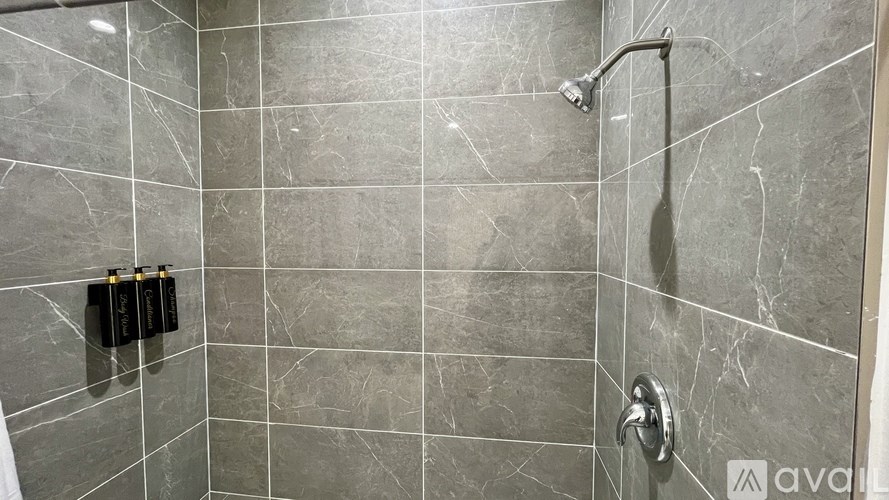 A bathroom with grey tiles and a silver faucet.
