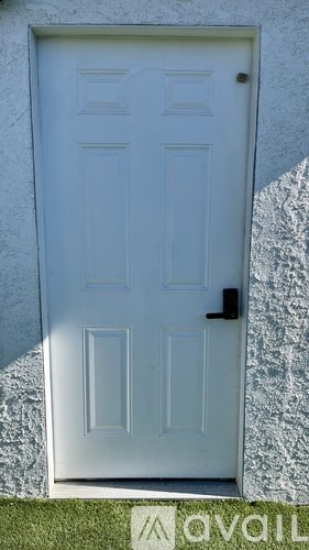 A white door with a black handle is set in a white wall.