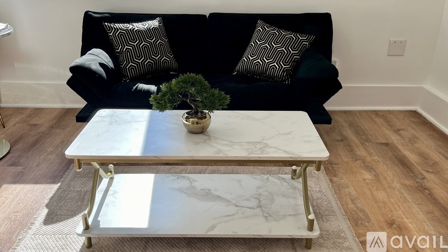 A black couch with a marble coffee table in front of it.