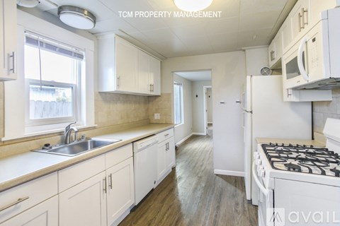A kitchen with white cabinets and a stove top oven.