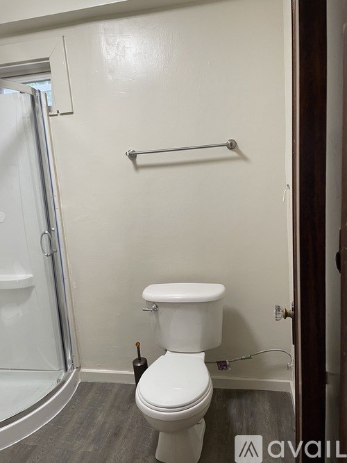 A white toilet in a small bathroom with a towel bar above it.