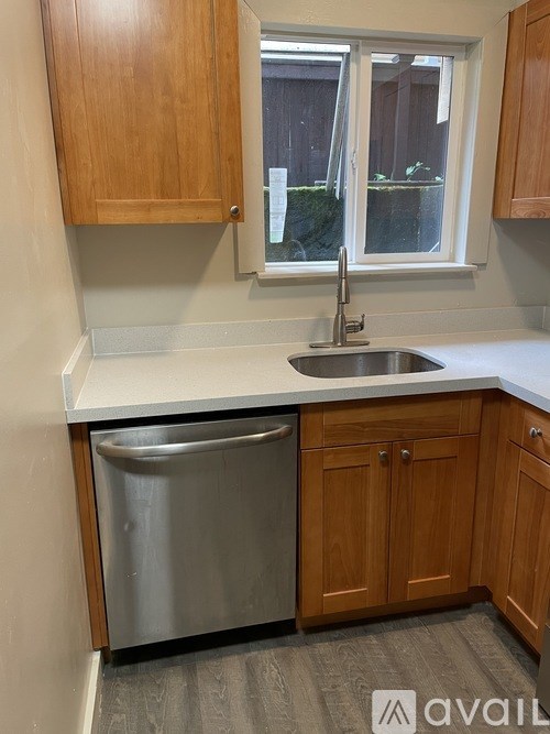 A kitchen with wooden cabinets and a stainless steel dishwasher.