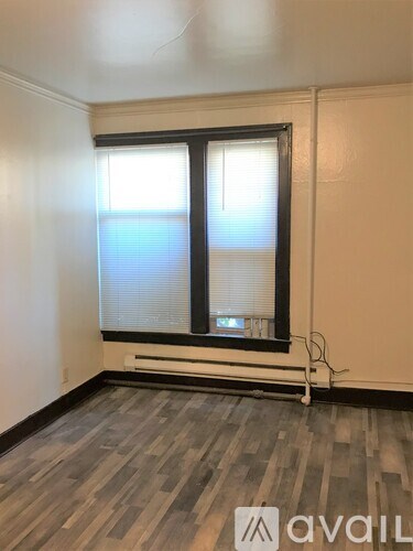 A room with a window and a wooden floor.