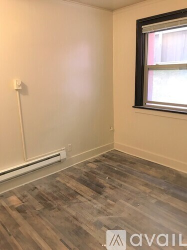 A room with a window and a wooden floor.