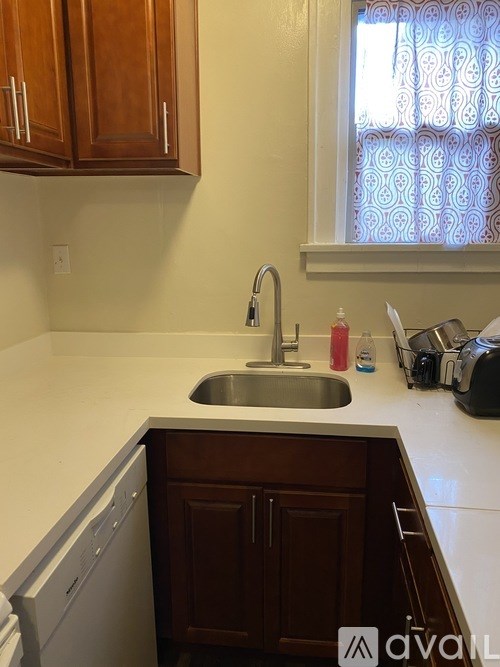 A kitchen with a sink and a window with curtains.