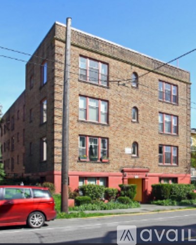 A tall brick building with a red car parked in front.