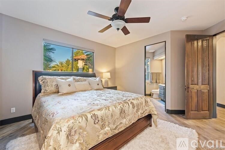 A bedroom with a large bed and a ceiling fan.