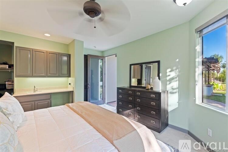 A bedroom with a large bed, a dresser, and a ceiling fan.