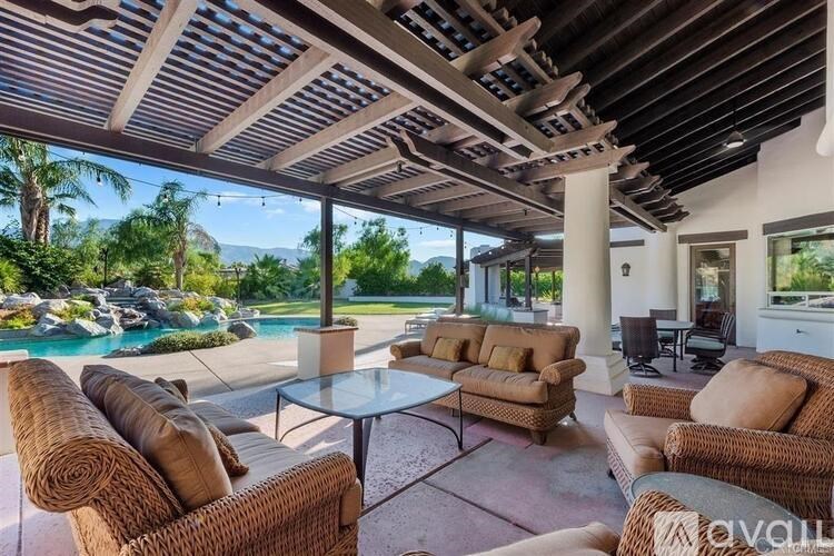 A patio with a table and chairs overlooking a pool.
