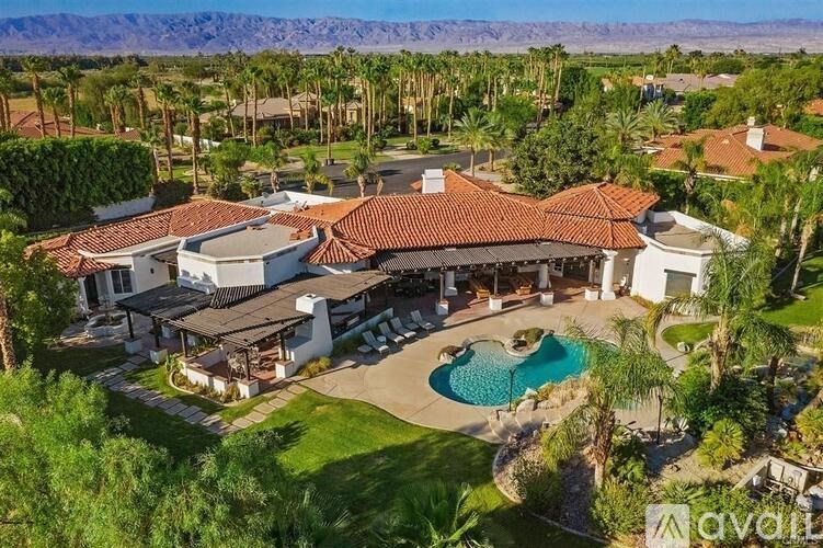A large house with a pool in the middle of a green lawn.