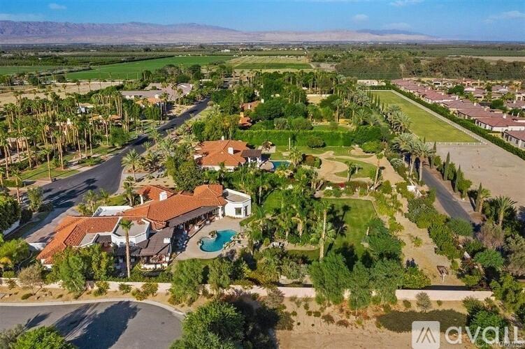 A bird's eye view of a residential area with houses, swimming pools, and palm trees.