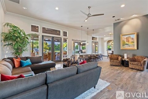 A spacious living room with a grey sofa and a ceiling fan.
