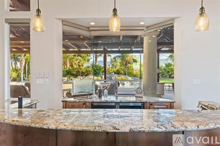 A kitchen with granite countertops and pendant lights.