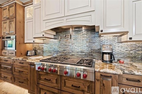 A kitchen with a stone backsplash and a stove top oven.