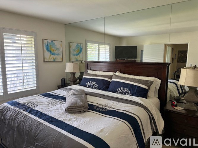 A bedroom with a large bed and a TV on the wall.