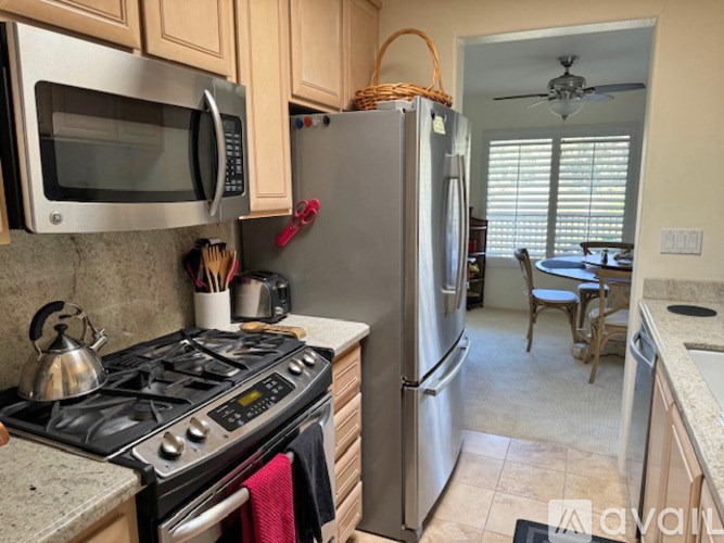 A kitchen with a stove, microwave, refrigerator, and a dining table with chairs.