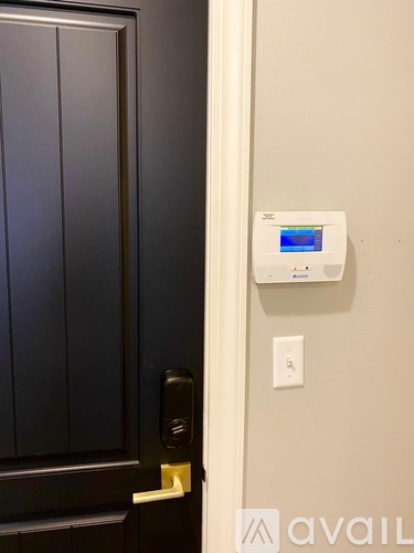 A black door with a white handle and a white wall with a thermostat on it.