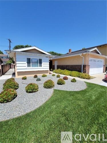 A house with a white exterior and a grey gravel pathway in front of it.