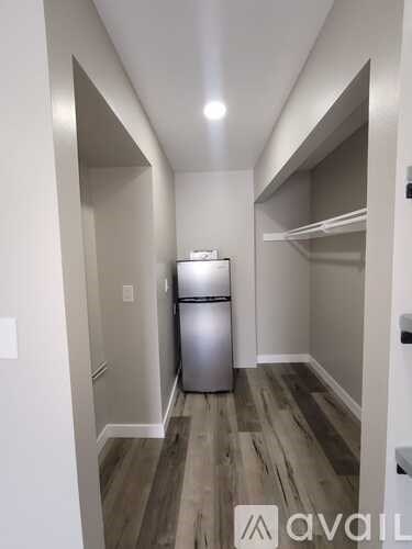 A kitchen with a fridge and wooden floors.