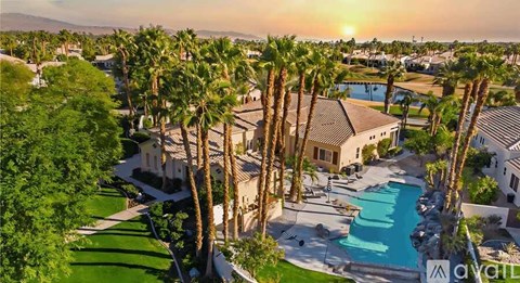 A sunset view of a pool surrounded by palm trees.