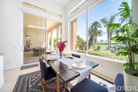 A dining room with a table set for two and a view of a backyard.