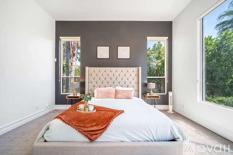 A bedroom with a large bed and a window overlooking trees.