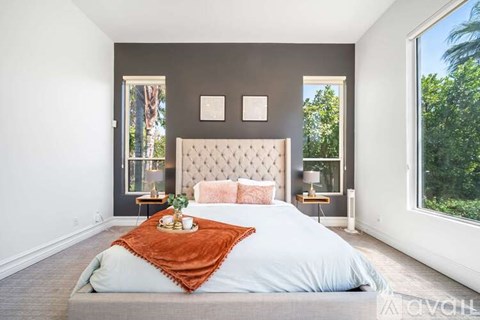 A bedroom with a large bed and a window overlooking trees.