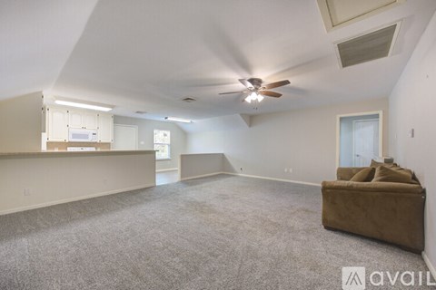 A spacious living room with a brown sofa and a ceiling fan.