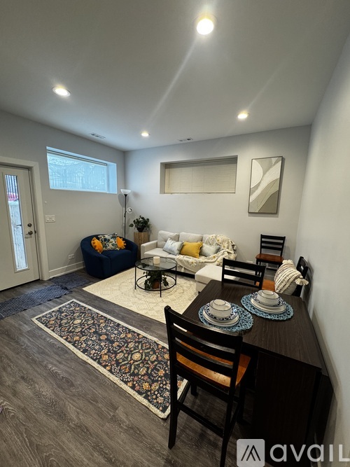 A living room with a couch, chairs, and a rug.