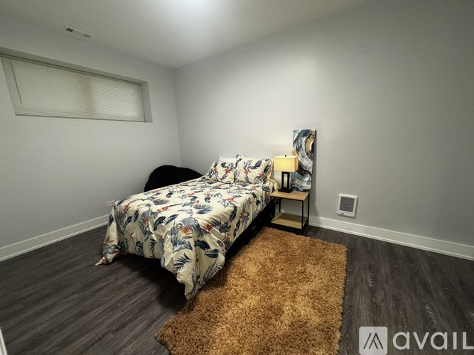 A bedroom with a floral bedspread and a brown rug.