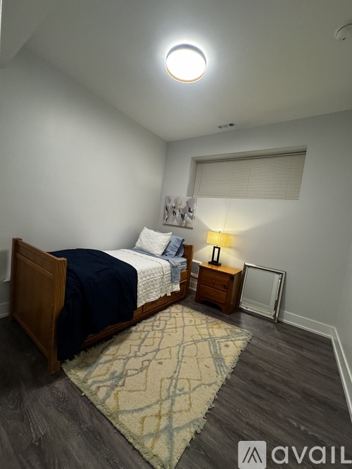 A bedroom with a bed, nightstand, and lamp.