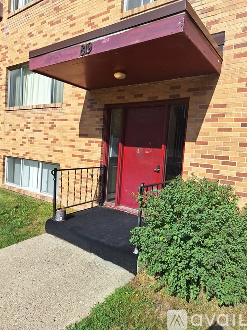 A red door is on the front of a brick building.