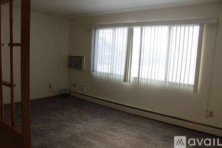 A room with a window covered by blinds and a small TV on the wall.