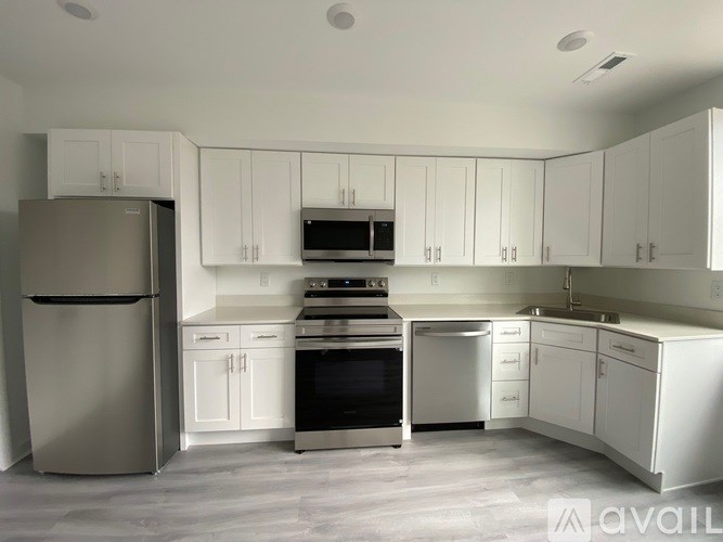 A modern kitchen with white cabinets and stainless steel appliances.
