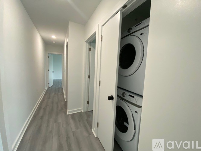 A long hallway with a washer and dryer in the doorway.