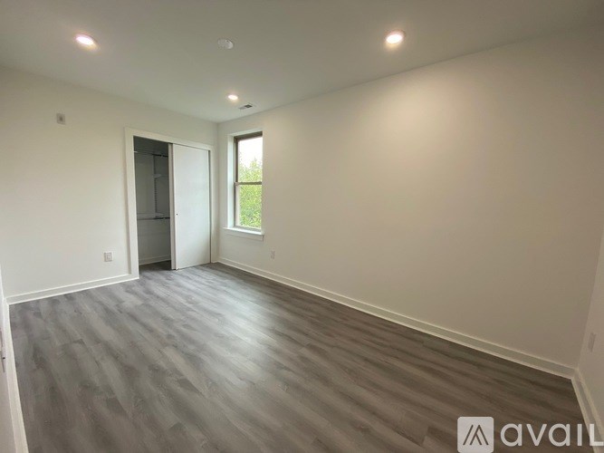 A spacious room with wooden flooring and a door leading to another room.