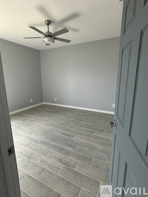A room with a ceiling fan and a door.