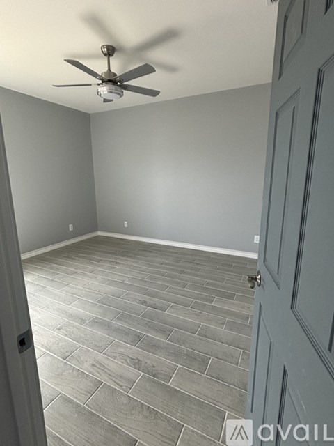 A room with a ceiling fan and a door.