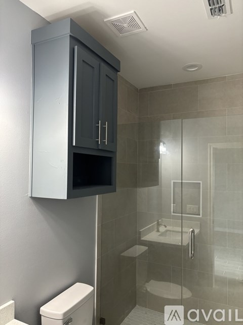 A bathroom with a toilet, sink, and cabinet.