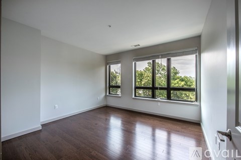 A spacious room with wooden floors and large windows.
