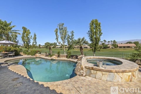 A pool surrounded by a stone patio and trees.